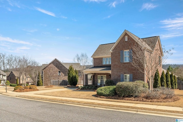 traditional-style house featuring fence and brick siding