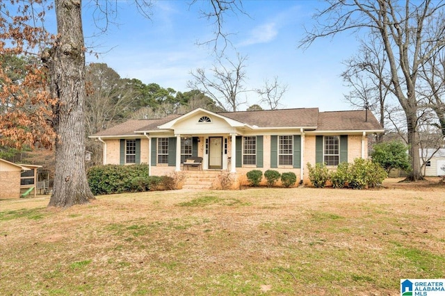 view of front of property with covered porch, a front lawn, and brick siding