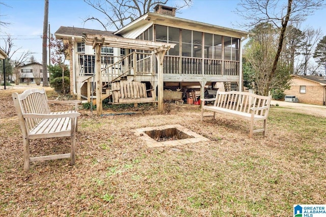 back of house with a sunroom, a chimney, and stairway