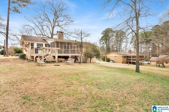 back of house with a sunroom, a chimney, stairway, and a yard