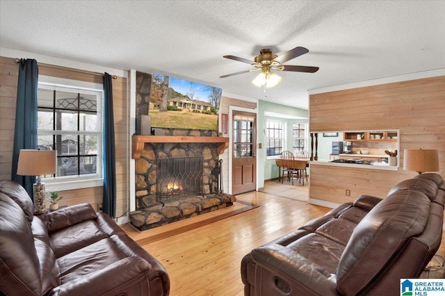 living room with a fireplace, wooden walls, a textured ceiling, and wood finished floors