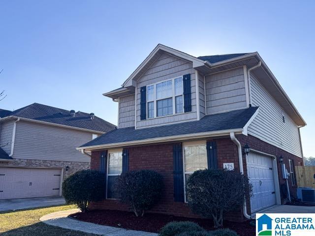 traditional home featuring a garage, central air condition unit, brick siding, and driveway