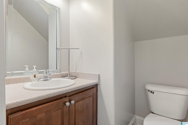 bathroom featuring toilet, vanity, and lofted ceiling