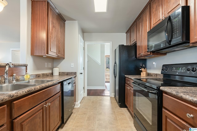 kitchen with a sink, baseboards, and black appliances