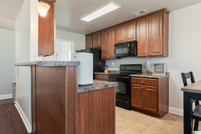 kitchen featuring visible vents, baseboards, brown cabinets, a peninsula, and black appliances