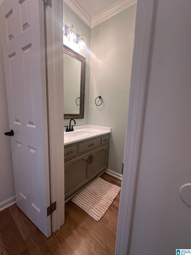 bathroom featuring baseboards, wood finished floors, vanity, and crown molding