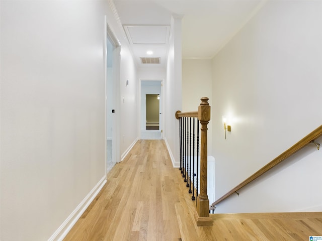 corridor with light wood-style flooring, an upstairs landing, visible vents, baseboards, and attic access