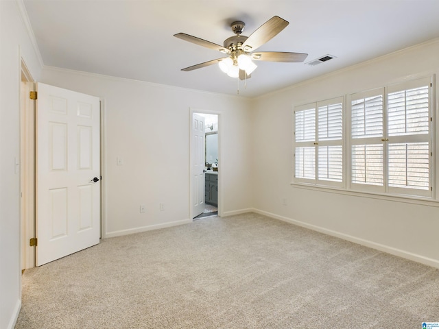 carpeted empty room featuring baseboards, a ceiling fan, visible vents, and crown molding