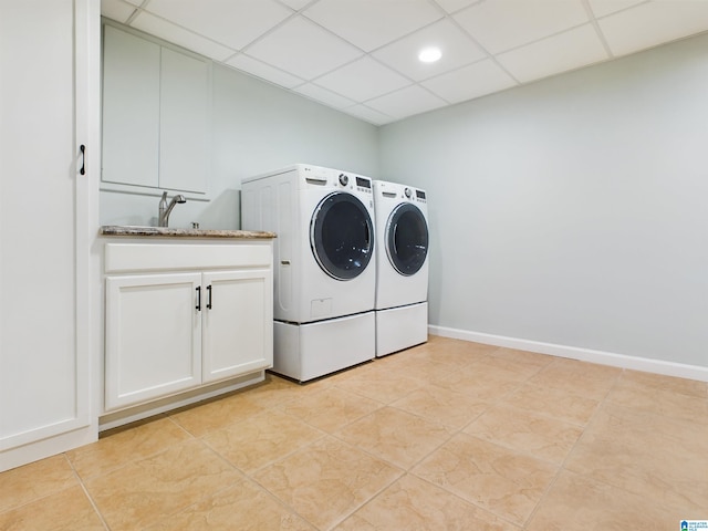 washroom with light tile patterned flooring, a sink, baseboards, washer and dryer, and cabinet space