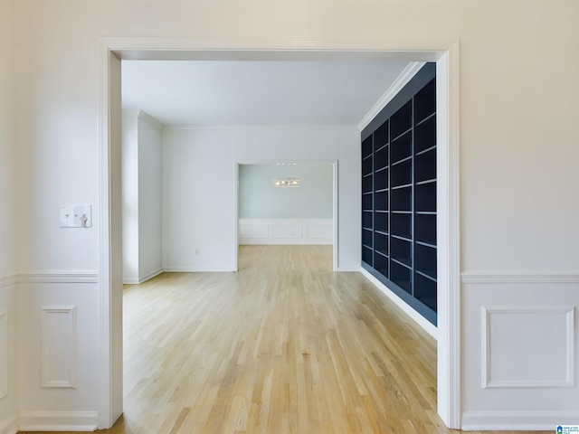 empty room with light wood-style flooring, ornamental molding, and a decorative wall