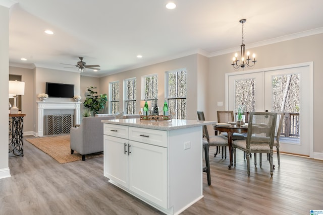 kitchen featuring white cabinetry, ornamental molding, a center island, light wood finished floors, and pendant lighting