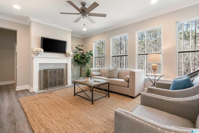 living room featuring a fireplace with flush hearth, crown molding, baseboards, and wood finished floors