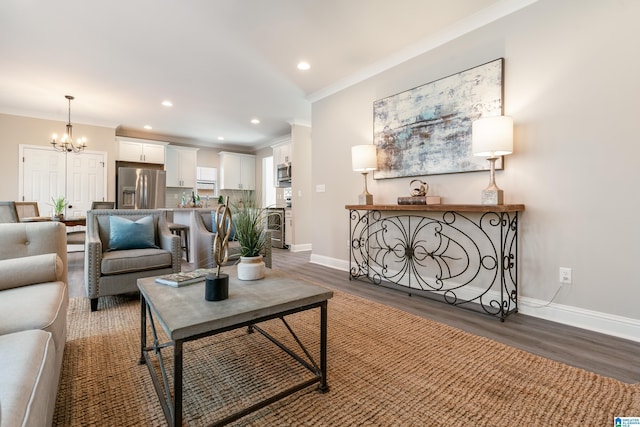 living room featuring baseboards, ornamental molding, wood finished floors, an inviting chandelier, and recessed lighting