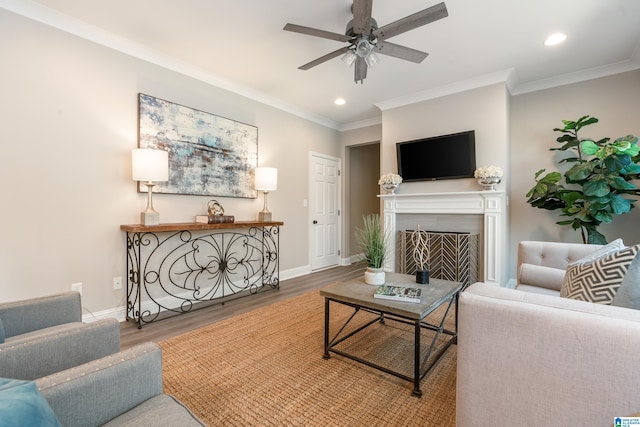 living area featuring a fireplace, recessed lighting, ornamental molding, wood finished floors, and baseboards