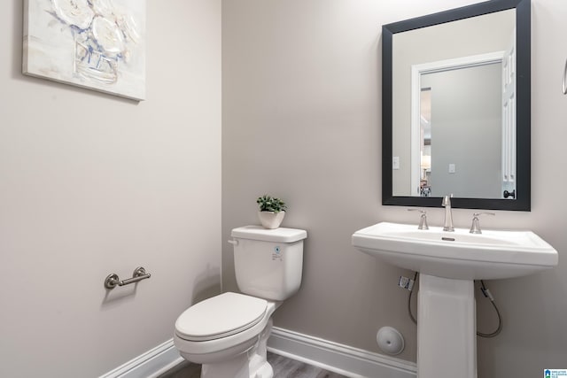 bathroom with wood finished floors, toilet, and baseboards