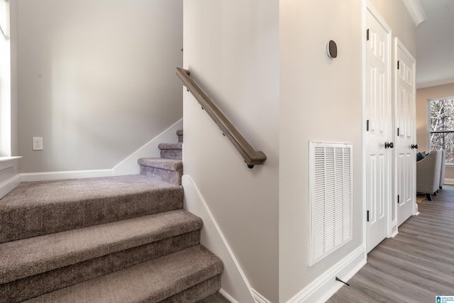 staircase with baseboards, visible vents, and wood finished floors