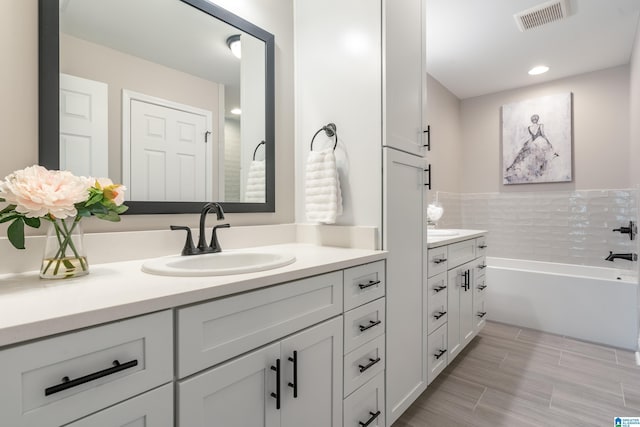 full bathroom featuring a bath, vanity, visible vents, and wood tiled floor