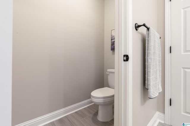 bathroom featuring toilet, baseboards, and wood finished floors