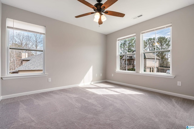 carpeted spare room with ceiling fan, visible vents, a wealth of natural light, and baseboards