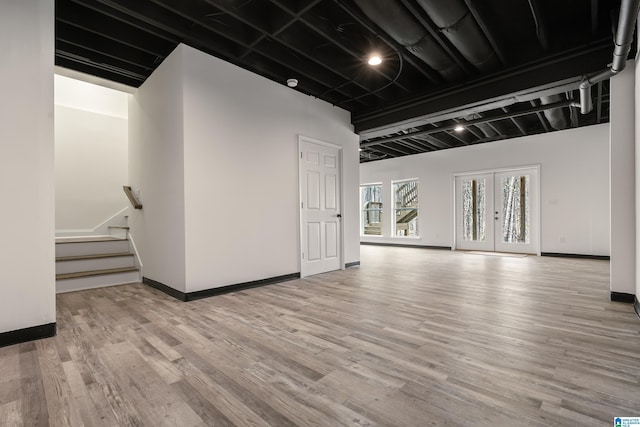 empty room featuring french doors, stairway, wood finished floors, and baseboards