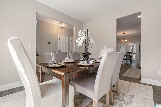 dining room with baseboards, visible vents, a chandelier, and wood finished floors