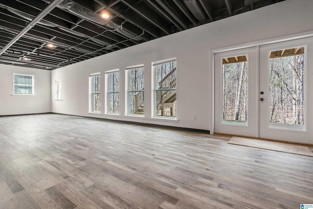 unfurnished living room featuring french doors, baseboards, and wood finished floors