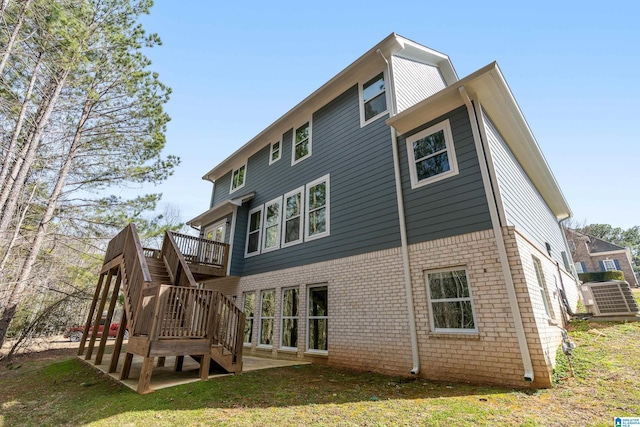 back of house featuring a yard, a wooden deck, stairs, and brick siding