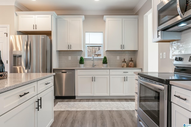 kitchen with tasteful backsplash, appliances with stainless steel finishes, white cabinets, and a sink