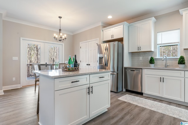 kitchen featuring crown molding, backsplash, appliances with stainless steel finishes, white cabinets, and a sink