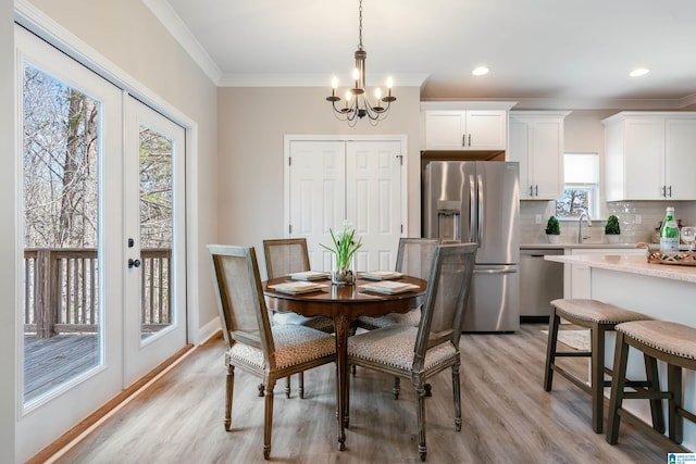 dining space featuring baseboards, light wood-style flooring, ornamental molding, an inviting chandelier, and french doors