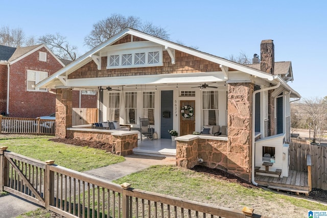 view of front facade featuring ceiling fan, a front lawn, a chimney, and fence