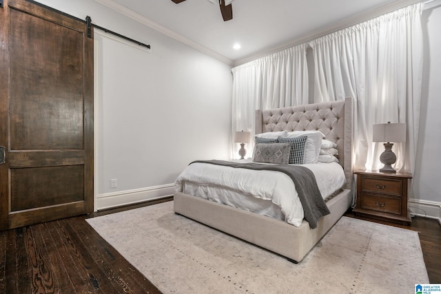 bedroom with dark wood finished floors, a barn door, ornamental molding, ceiling fan, and baseboards