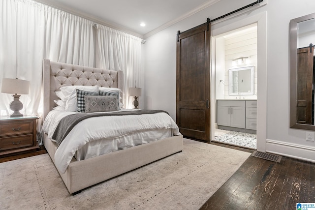 bedroom featuring ornamental molding, light wood-type flooring, visible vents, and a barn door