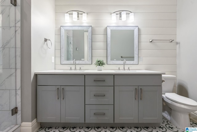 bathroom with toilet, a stall shower, double vanity, and a sink