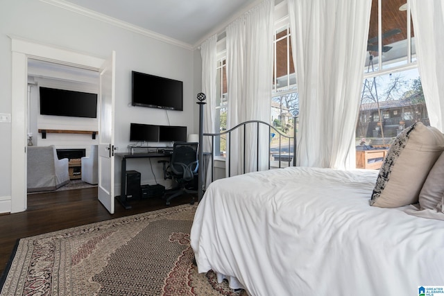 bedroom featuring access to exterior, dark wood-style flooring, multiple windows, and crown molding