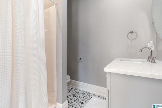 full bath with a stall shower, tile patterned flooring, baseboards, and vanity