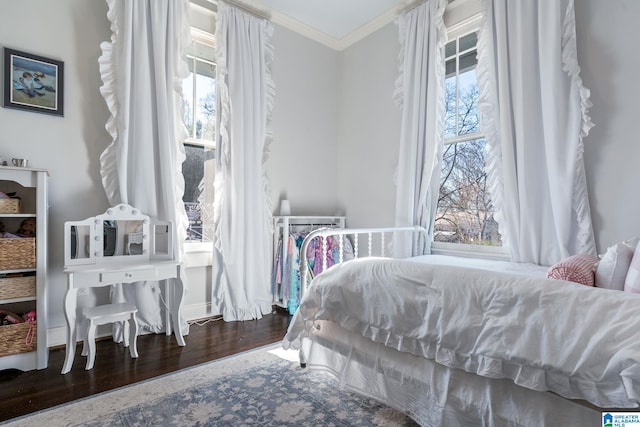 bedroom featuring dark wood-style flooring, ornamental molding, and multiple windows