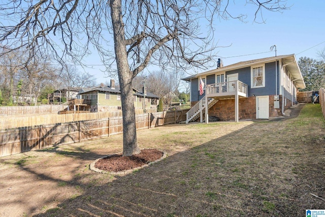 rear view of property with a lawn, stone siding, a fenced backyard, a chimney, and stairs