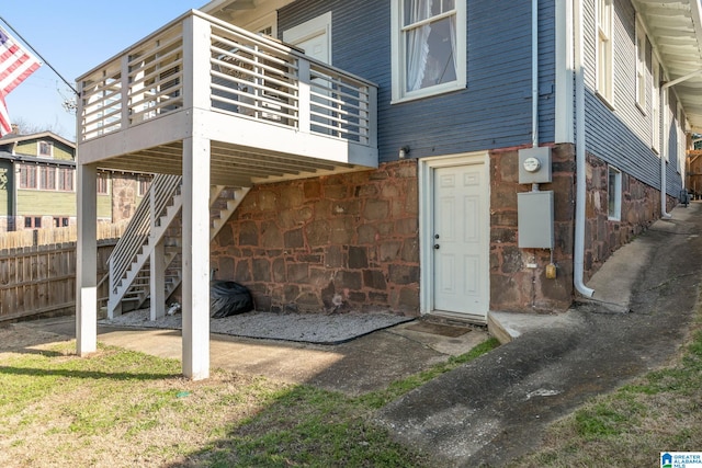 back of house with stone siding, a deck, and stairs