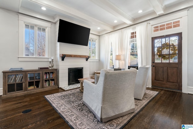 living area with a large fireplace, beamed ceiling, dark wood finished floors, and crown molding