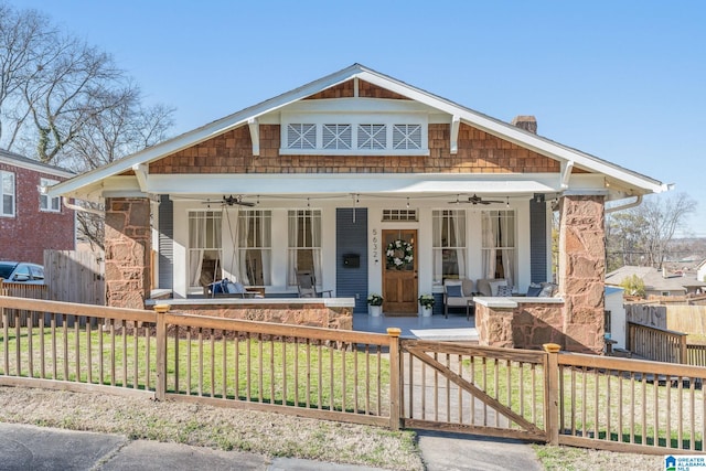 view of front facade with a fenced front yard, a ceiling fan, a gate, a front lawn, and a chimney