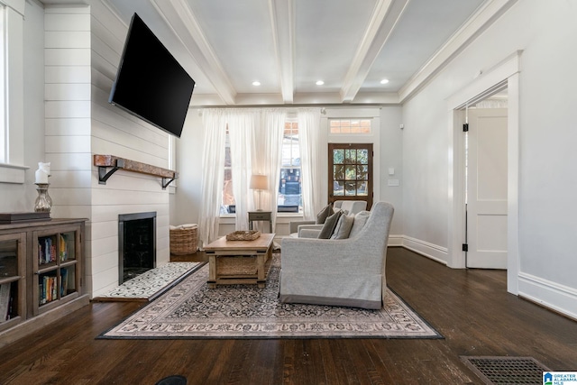 sitting room with a large fireplace, baseboards, visible vents, dark wood finished floors, and beam ceiling