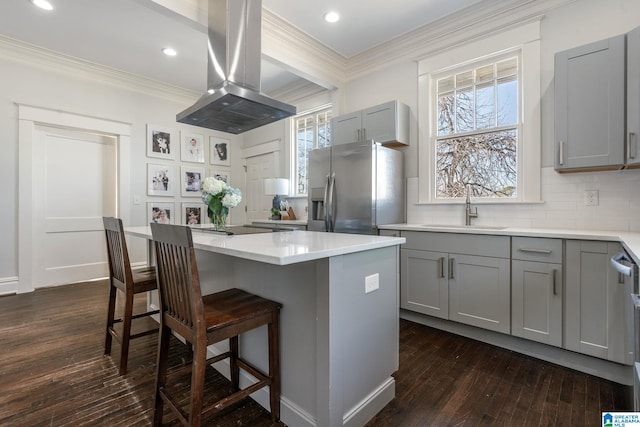 kitchen with island range hood, stainless steel fridge with ice dispenser, a center island, light countertops, and a sink