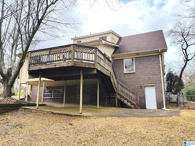 back of property featuring a shingled roof, brick siding, a wooden deck, and stairs