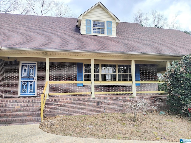 view of front of home featuring brick siding and roof with shingles