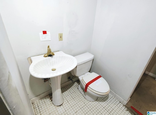 bathroom with toilet, baseboards, a sink, and tile patterned floors