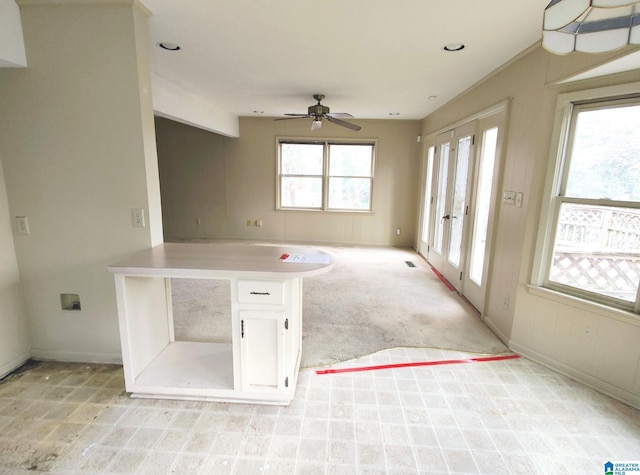 empty room with a ceiling fan, a wealth of natural light, light carpet, and baseboards