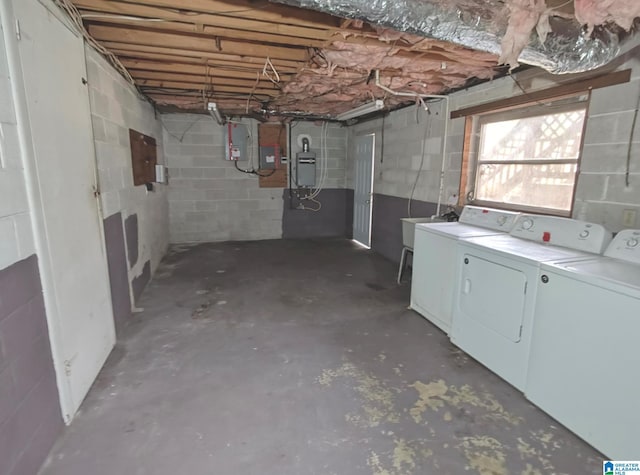 below grade area featuring concrete block wall, electric panel, a sink, and washing machine and clothes dryer