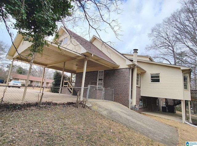 view of front of home featuring a carport, brick siding, and fence