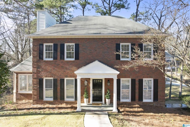 view of front of home featuring brick siding and a chimney